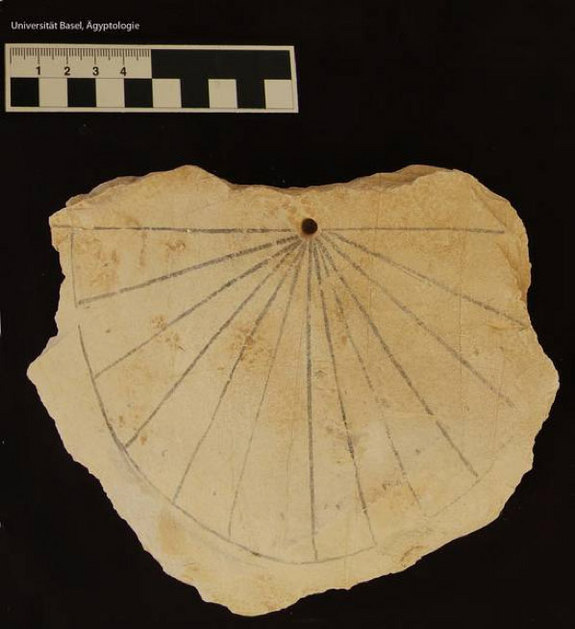 A photograph of an ancient Egyptian sundial and a stone water clock displayed in a museum, both bearing marked divisions.