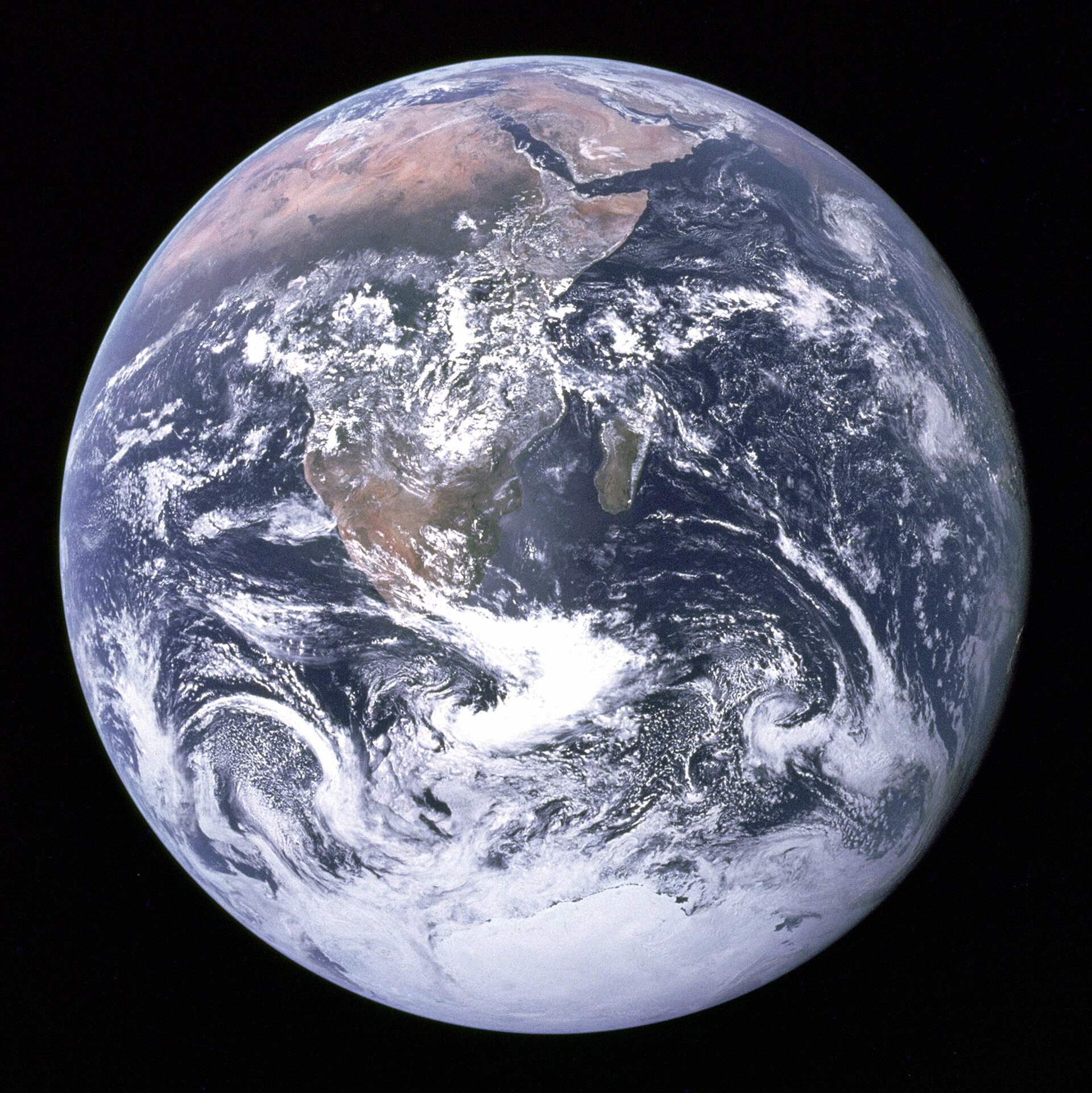 The Blue Marble: the full disc of Earth photographed from space, showing Africa, Antarctica and swirls of white cloud against black.