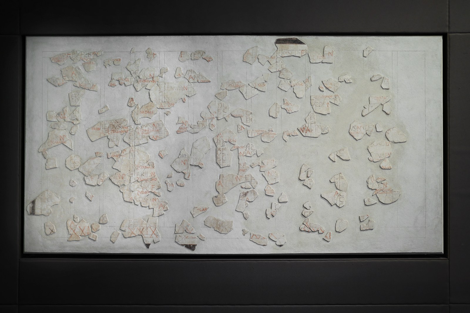 A fragmentary ancient Roman wall-painted calendar panel with rows of Latin month names, one month marked with intercalary letters.
